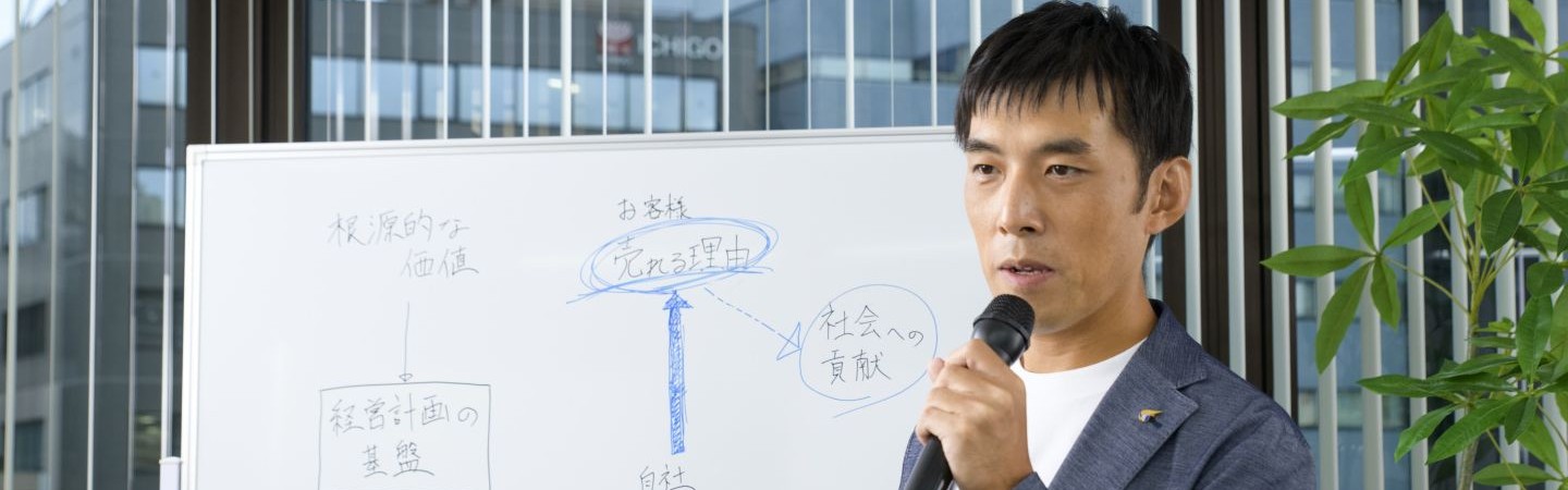 ホワイトボードで経営計画を説明する代表